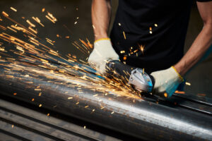 angle grinder for grinding metal in male hands grinds metal pipe with sparks. High quality photo