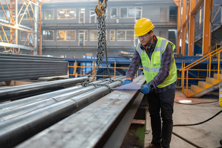 Male Metal Worker Looking At Blueprint In An Industrial Factory