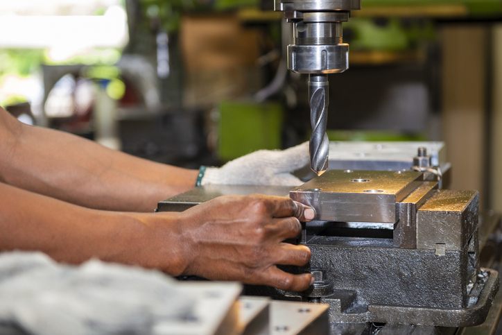 The machine operator hold the metal plate with NC milling machine. The shop floor operation by NC milling machine.